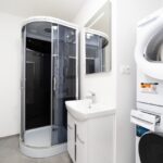 Kúpeľňa so sprchovacím kútom, práčkou a sušičkou – byt Venevská